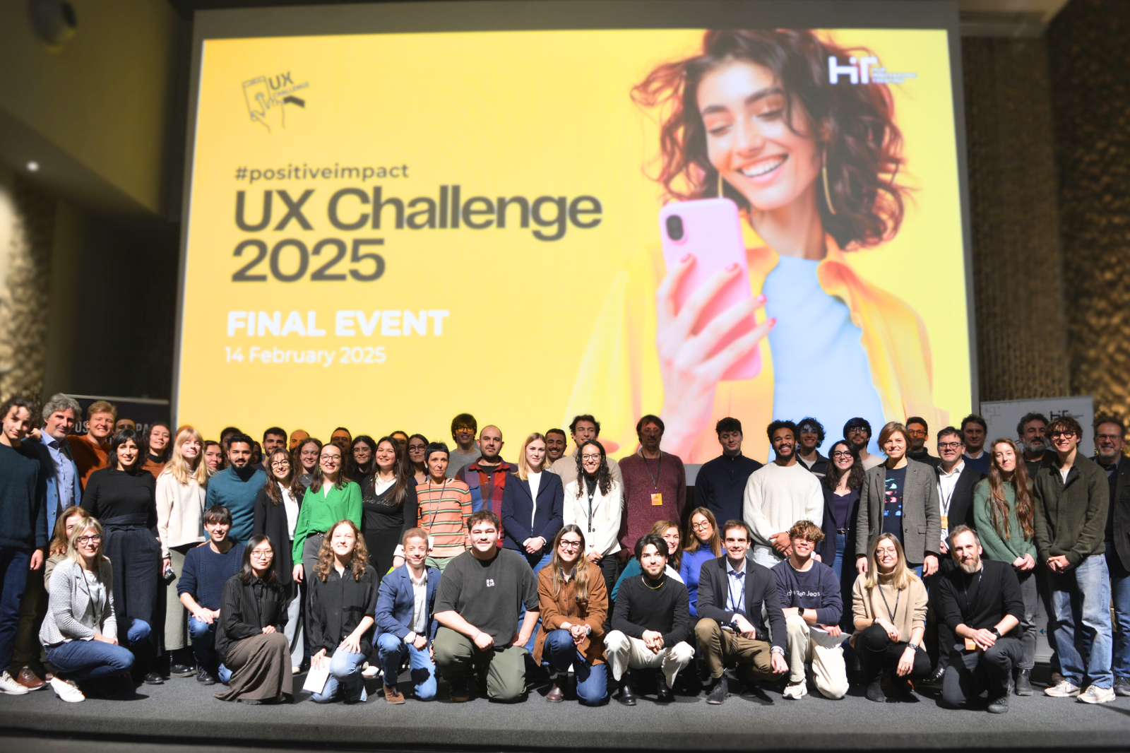 Participants of the UX Challenge 2025 final event gathered on stage in front of the event backdrop