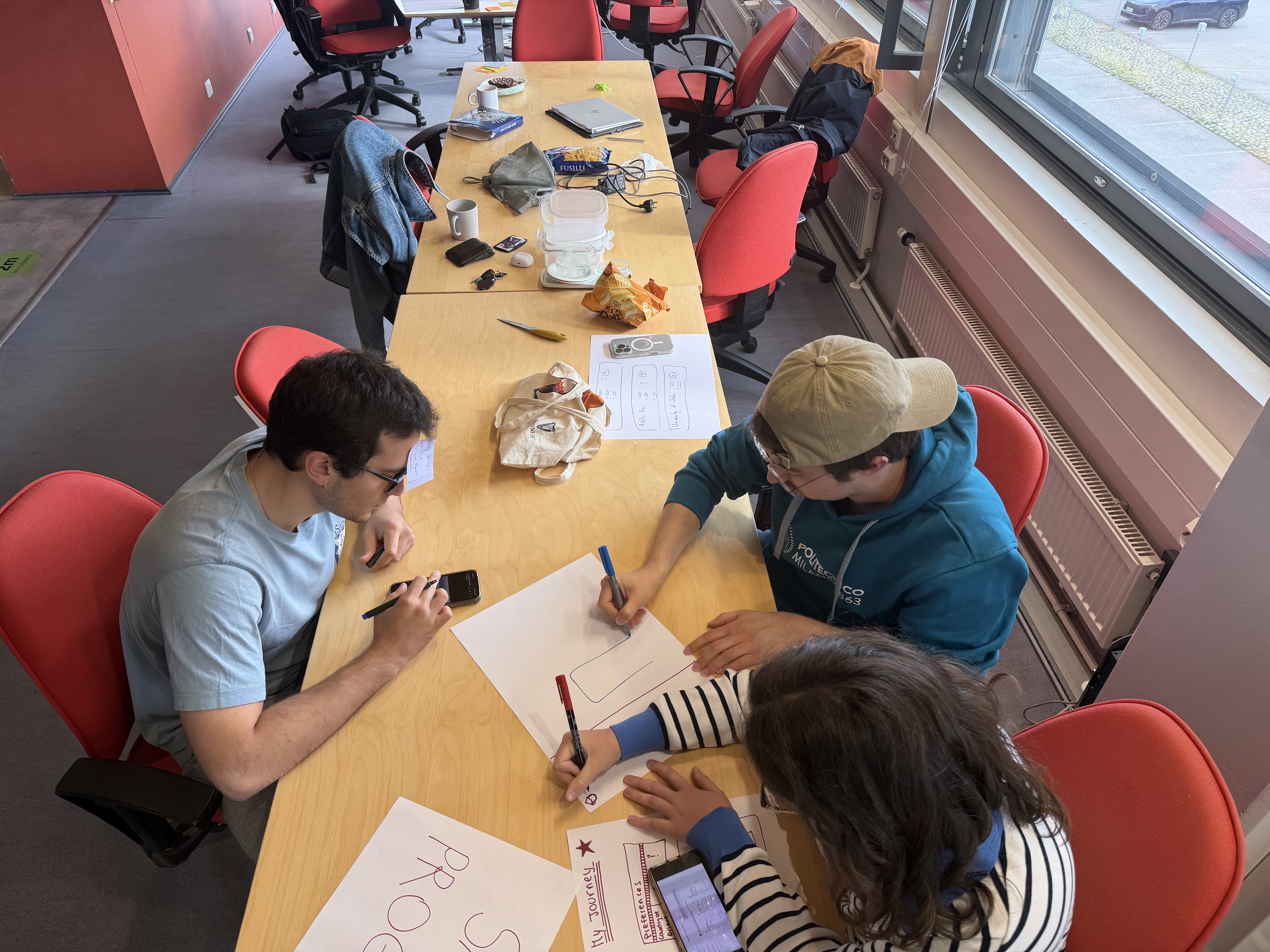 Four students around a table in a participatory design session, sketching interface ideas on paper